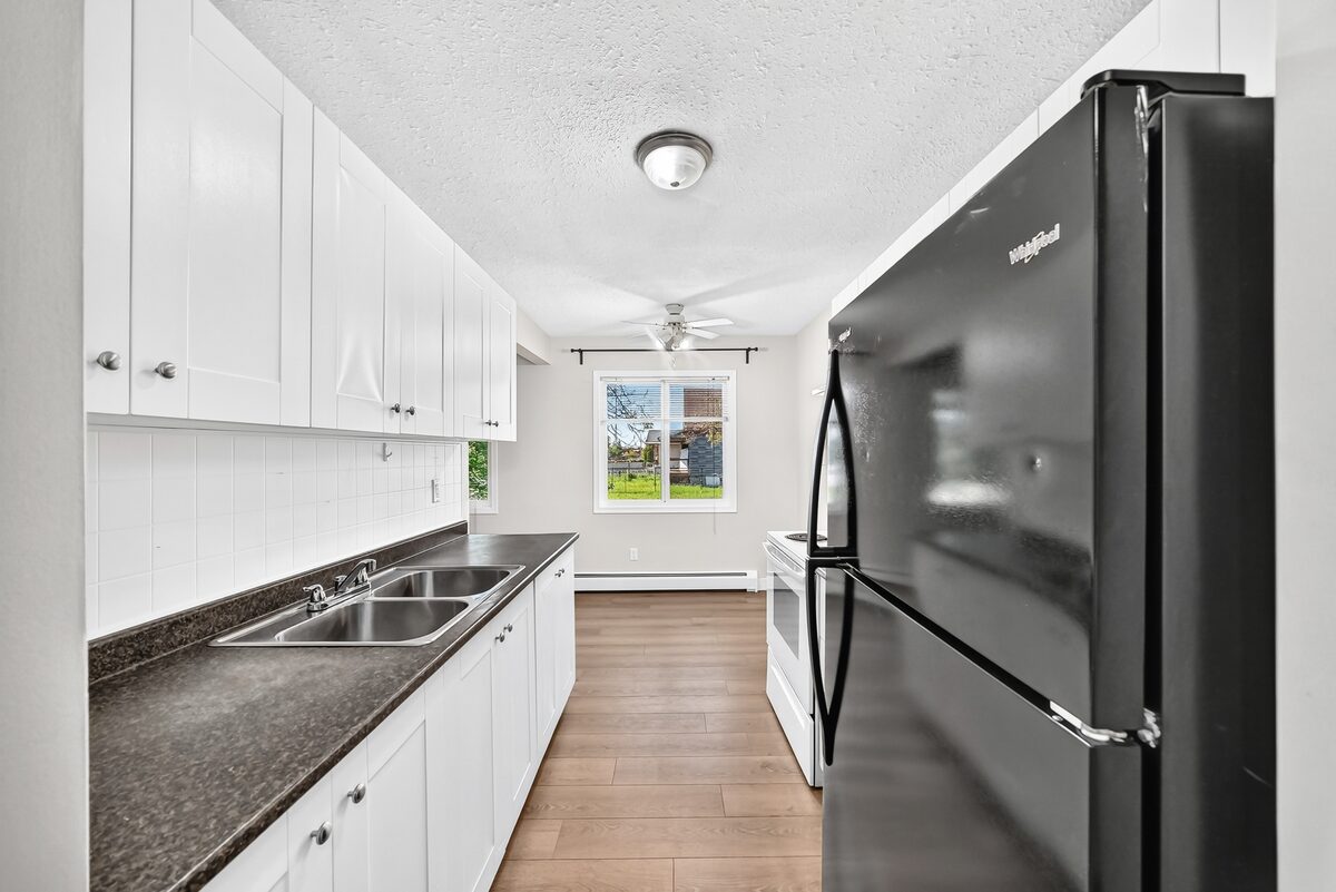 Renovated kitchen with white cabinetry and full-size fridge