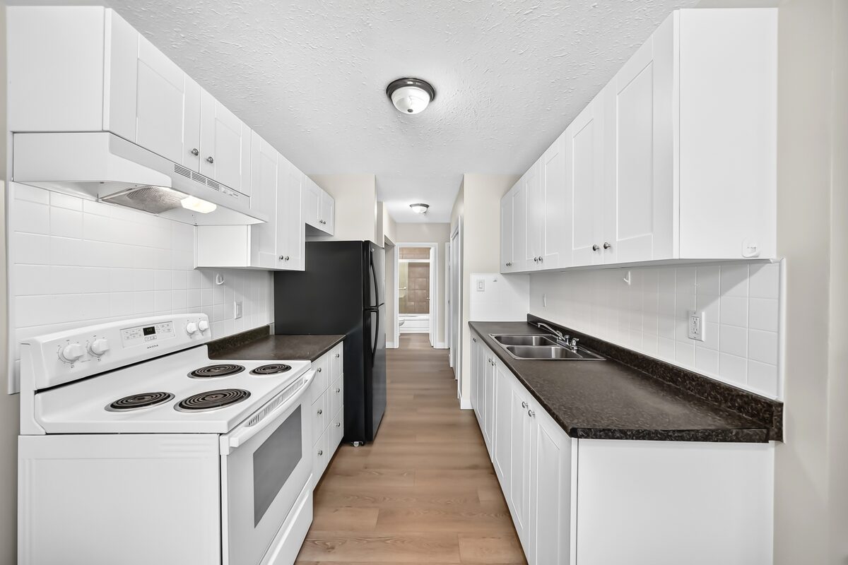 Galley kitchen with white cabinets, stove and updated counters